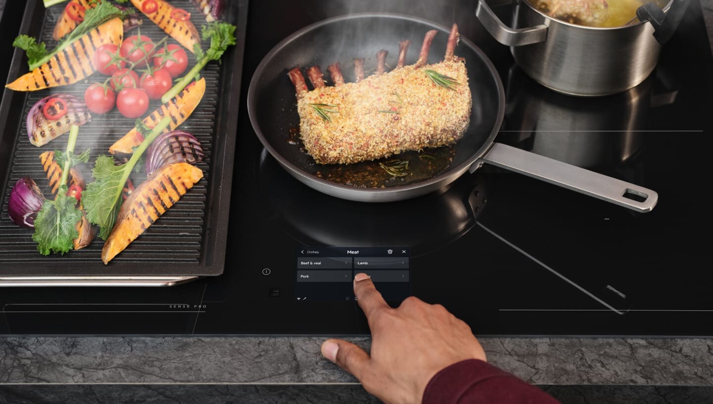 Ett finger rör vid kontrollpanelen på en induktionshäll.