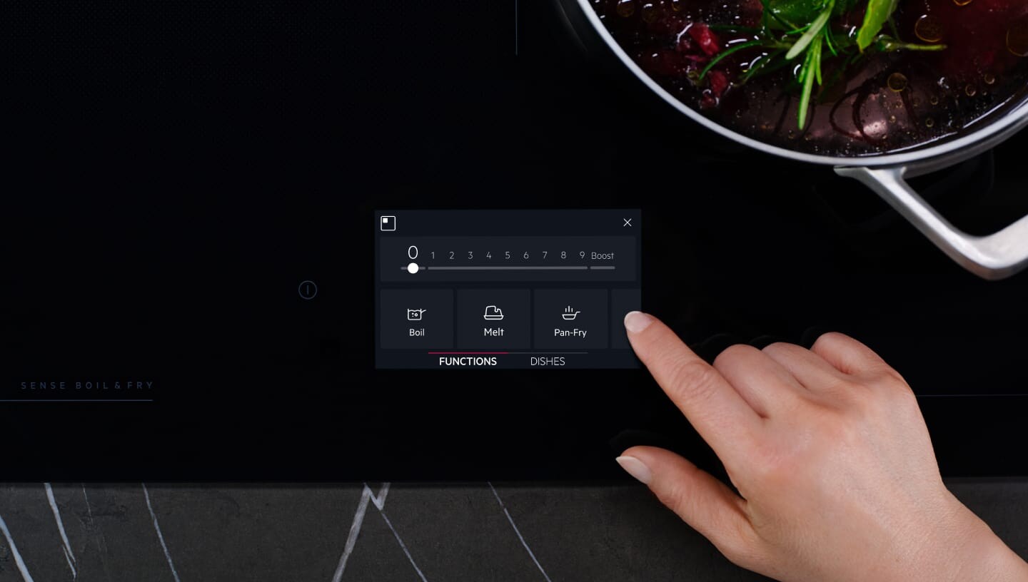 Ett finger rör vid kontrollpanelen på en induktionshäll.