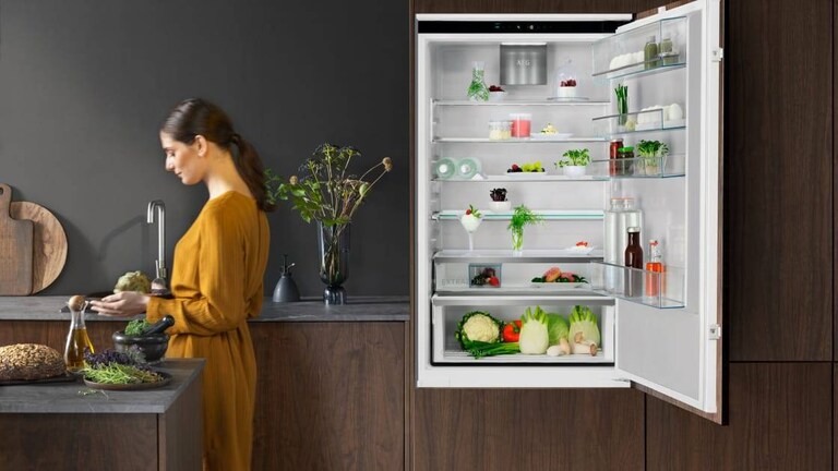 Kvinna som står i ett kök med en öppen kylskåpsdörr