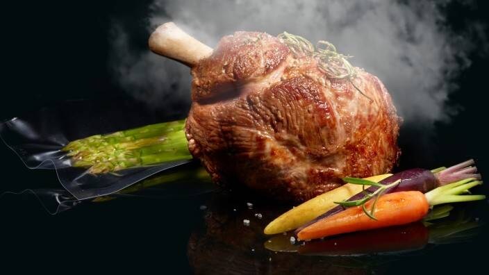 Ångat kött med vakuumförpackade grönsaker på en köksbänk.