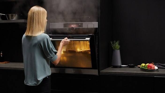En kvinna tittar till maten i sin ångugn.