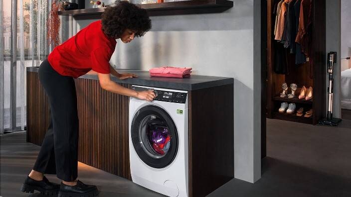 En kvinna startar igång en färgad tvätt i en tvättmaskin från AEG.