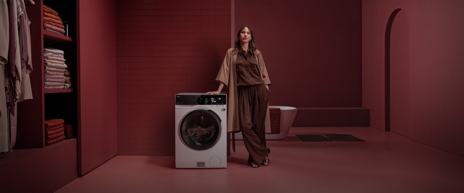 Kvinna står bredvid en fristående tvätt- och torkmaskin i ett rött rum
