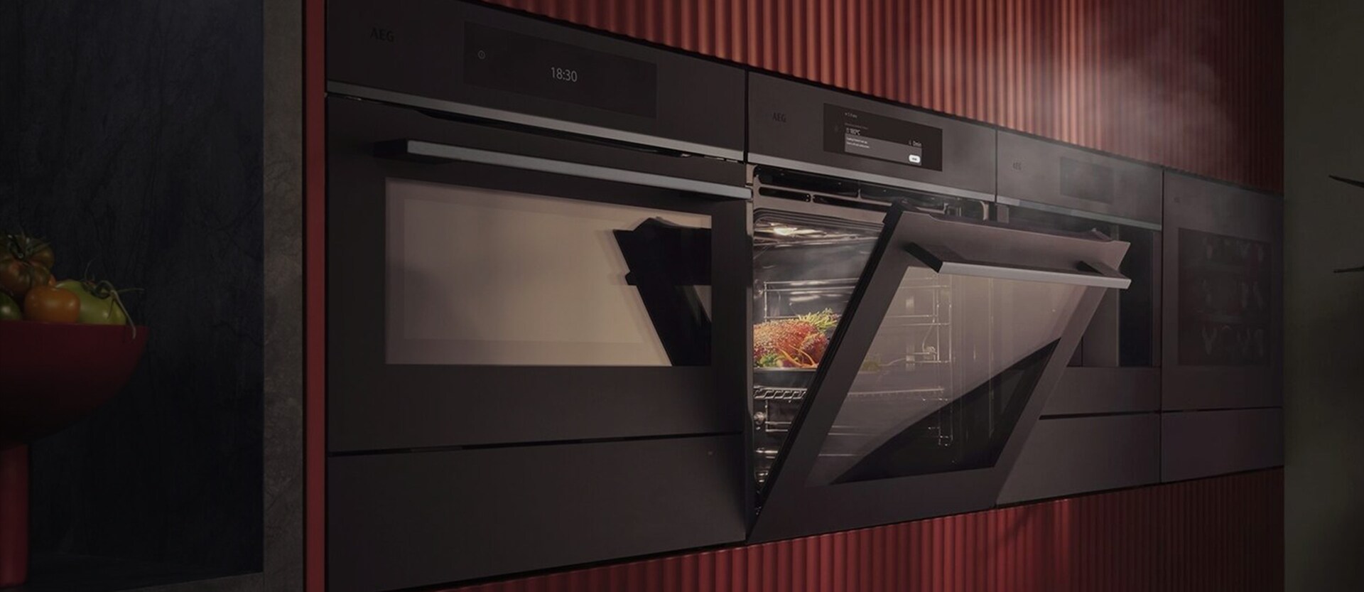 En inbyggd AEG ångugn i en modern köksvägg med röda räfflade paneler som visar matlagning med ånga
