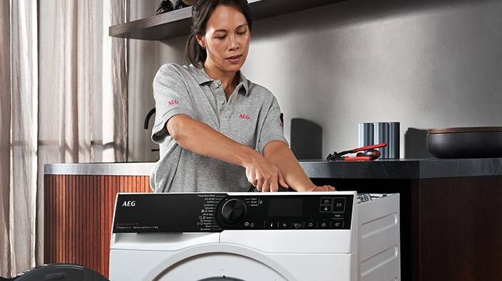 Kvinna reparerar tvättmaskin